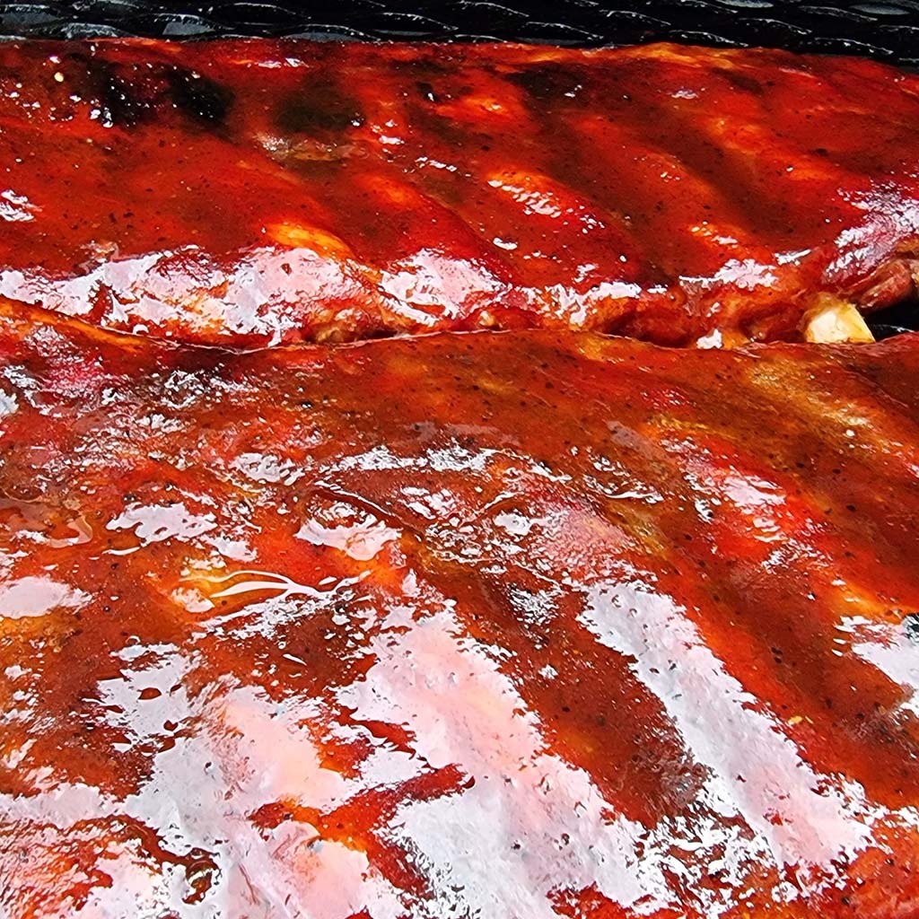 Grilled ribs glazed with Sweet Texas BBQ Sauce by Firefly, showcasing a rich, glossy finish perfect for enhancing BBQ dishes with sweet tangy flavor.
